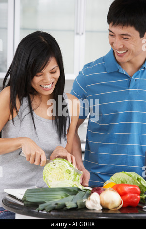 Asian couple chopping vegetables in kitchen Stock Photo