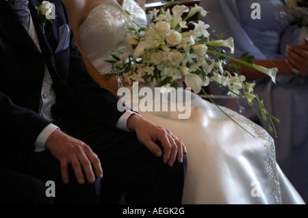 grooms hand showing wedding ring during wedding ceremony with bride in the background with flowers Stock Photo