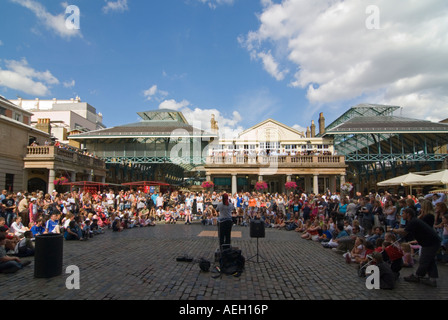 Horizontal wide angle of a street performer entertaining the crowds in the Piazza at Covent Garden on a bright sunny evening Stock Photo