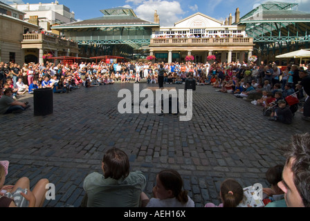 Horizontal wide angle of a street performer entertaining the crowds in the piazza at Covent garden on a bright sunny evening Stock Photo