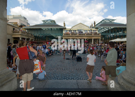 Horizontal wide angle of a street performer entertaining the crowds in the piazza at Covent Garden on a sunny evening Stock Photo