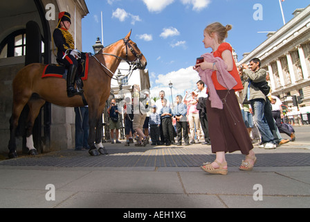 Horizontal wide angle of a female member of the Household Cavalry at Horse Guards Parade in Whitehall surrounded by tourists. Stock Photo