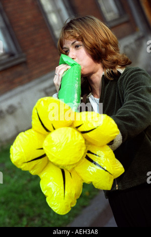 Welsh rugby fan blowing up an giant inflatable daffodil before a Wales international match in Cardiff Stock Photo