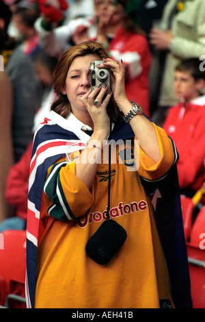 Female Australia rugby fan draped Australian flag taking a photographs in the Millennium Stadium Cardiff South Wales UK Stock Photo