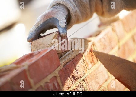 WORKERS HANDS WITH TROWEL LAYING BRICKS WITH MORTER ON A CONSTRUCTION SITE IN THE UK, BUILDING Stock Photo