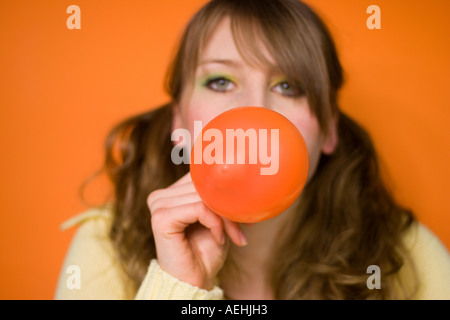 Young woman blowing up balloon Stock Photo