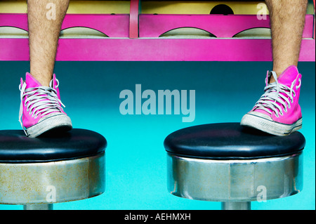 Close up of man’s feet in pink sneakers on stools Stock Photo