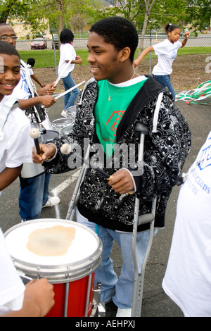 Black handicapped drummer on crutches wears Boys and Girls club shirt in parade. Cinco de Mayo Fiesta. 'St Paul' Minnesota USA Stock Photo