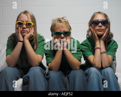 three adolescents sitting on white sofa Stock Photo