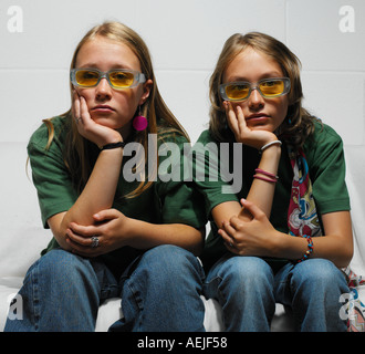 two adolescent girls sitting on white sofa Stock Photo