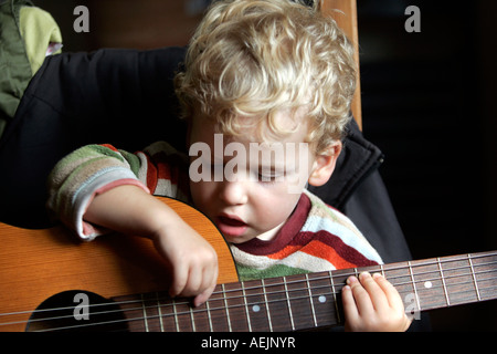 Two year old Simon plays the guitar Stock Photo