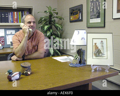 Male talks on telephone while working at his desk in an office Stock Photo