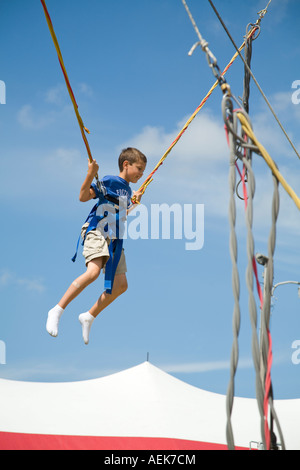 ILLINOIS Grayslake Young boy on bungee bounce swings at Lake County Fair safety harness and ropes Stock Photo