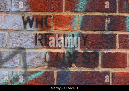 Graffiti on wall with the message who really cares, London England UK Stock Photo