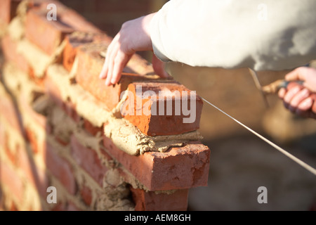 WORKER  LAYING BRICKS WITH MORTER ON A CONSTRUCTION SITE IN THE UK, BUILDING A HOUSE Stock Photo