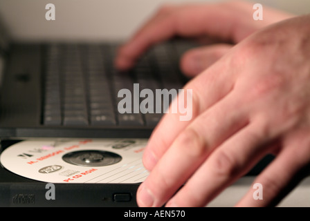 Man Inserting a Disc Into the CD Rom Drive of a Laptop Computer Stock Photo