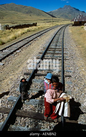 Lady and her children selling toys on railway track, near La Raya, Puno to Cusco Perurail train journey, Peru Stock Photo
