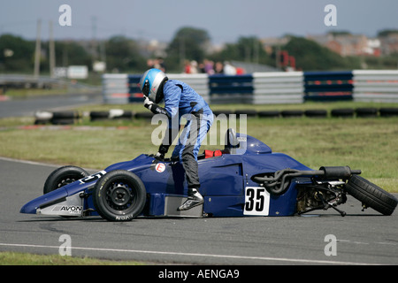 Kris Loane from Kesh climbs out of his crashed blue Van Diemen RF92 Formula Ford FF 1600 at Kirkistown Circuit county down Stock Photo