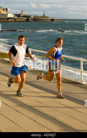 two people running runners training on the promenade Aberystwyth Ceredigion West Wales UK Stock Photo