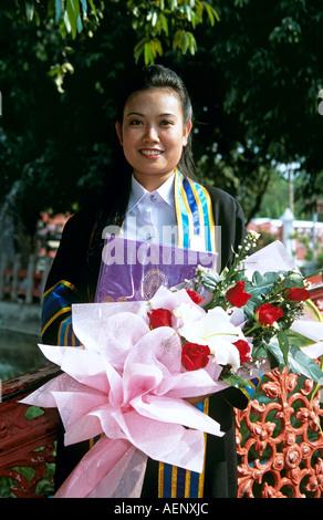 Graduate holding a bouquet of flowers at a graduation ceremony, Bangkok, Thailand Stock Photo