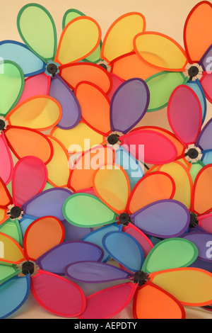 Mass of 6 petaled multi colored windmills grouped together against a beige background. Stock Photo