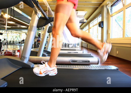 Young woman is training with a treadmill ,Junge Frau laeuft auf einem Laufband in einem Fitnessstudio Stock Photo