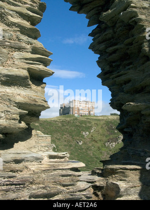 Tintagel Hotel, or Camelot Castle Hotel, viewed through a hole in the ancient stone wall of Tintagel Castle, Kernow, Cornwall, U Stock Photo