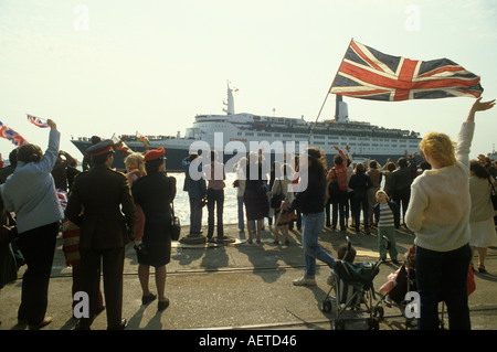 Queen Elizabeth II QE2 ship leaves for the Falklands War May 12th 1982, Southampton Dock. Families wave a Union Jack flag and goodbye England UK 1980s. Stock Photo