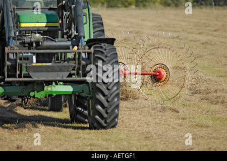 Farmer Harvesting cutting hay in Florida FL and bailing it to cubes with egrets looking for bugs with John Deere Tractor Stock Photo