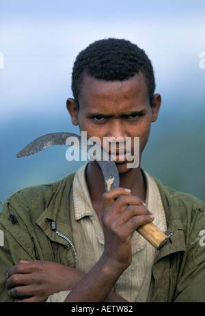 Portrait of a young man holding a sickle Oromo country Bako region Shoa state Ethiopia Africa Stock Photo