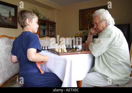 Chess match between young grandson and old grandfather Stock Photo