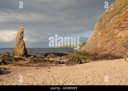 Red rock quartzite sea stacks on the shore at picturesque fishing village, Cullen Bay, Moray coast, Scotland UK Stock Photo
