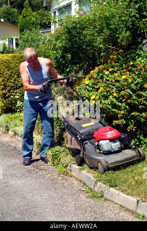 A professional gardener using his rotory lawn mower to cut the grass in a parkland area. Stock Photo