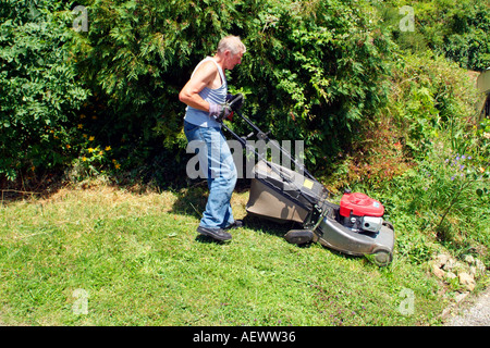 A professional gardener using his rotory lawn mower to cut the grass in a parkland area. Stock Photo