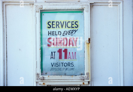 Professionally handpainted poster in glass-fronted case stating Services held every Sunday at 11 am Visitors especially welcome Stock Photo