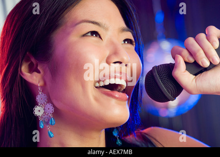 Woman singing into microphone Stock Photo