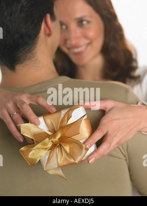 Woman holding gift with arms around man Stock Photo