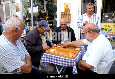 Typical Greek Street Scene. A bunch of men gathered around a table watching a game of backgammon / Tavli Stock Photo