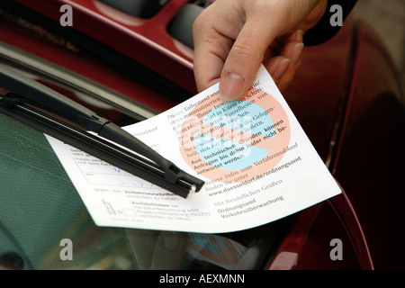 Traffic warden distributes parking ticket to parking offenders Stock Photo