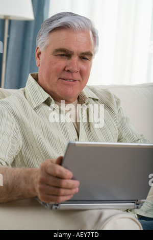 Senior man using laptop on sofa Stock Photo