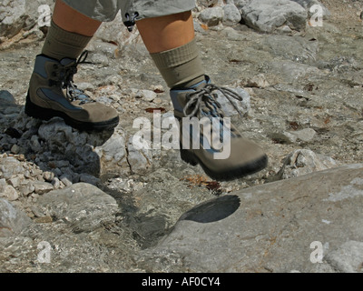 MR hiking in the mountains walking over stones scree with walking hiking shoes legs of a woman Stock Photo