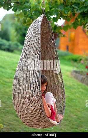 Hanging wicker basket chair, girl using hanging basket chair Stock Photo