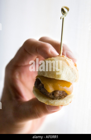 Woman holding mini cheeseburger at cocktail party Stock Photo