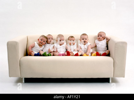 Six babies sitting on a sofa Stock Photo
