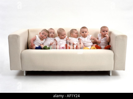 Six babies sitting on a sofa Stock Photo