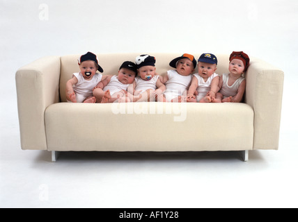 Six babies sitting on a sofa Stock Photo