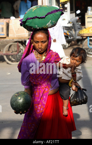 Rabari tribal woman with child selecting melon at market stall, Una, Gujarat, India