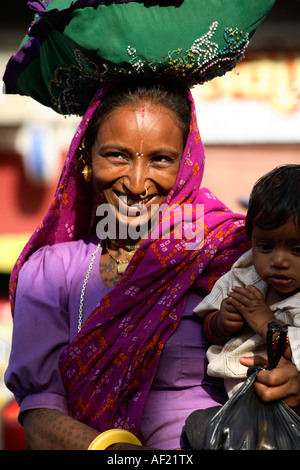 Rabari tribal woman with neck and arm tattoos selecting fruit at market stall, Una, Gujarat, India