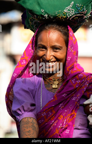Attractive Rabari tribal woman with neck and arm tattoos selecting fruit at market stall, Una, Gujarat, India