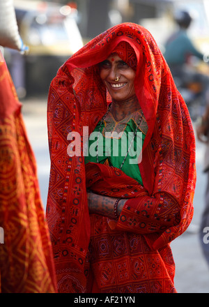 Rabari Tribal woman with neck and arm tattoos shielding face from sunlight, Una, Gujarat, India